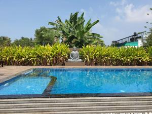 une statue assise à côté d'une piscine dans l'établissement Alleppey Haven Beach Villa, à Alappuzha