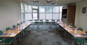 a conference room with long tables and green chairs at Campanile Paris Ouest - Gennevilliers Barbanniers in Gennevilliers
