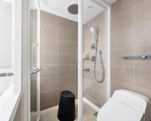 a bathroom with a shower and a toilet at remm plus Kobe Sannomiya in Kobe +17 photos