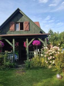 una casa con flores delante en Zielony Domek z jacuzzi nizsza cena min 4 dni, en Kopalino