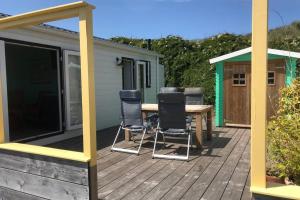 una terraza con sillas, una mesa y una casa en Summer house on the Dutch coast en IJmuiden