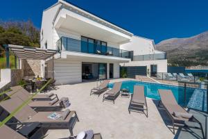 a villa with a swimming pool and lounge chairs at Ville Sol Del Mar in Slano