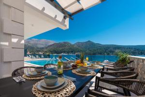 a dining table with a view of the water and mountains at Ville Sol Del Mar in Slano +133 photos