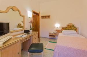 a bedroom with a bed and a desk with a mirror at Hotel Parco Smeraldo Terme in Ischia