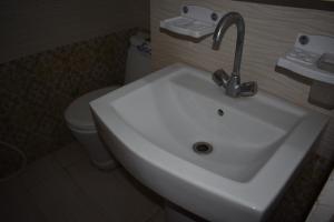 a white sink in a bathroom with a toilet at Hotel Kashmir Inn in Rawalpindi