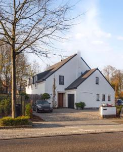 een wit huis met een auto ervoor geparkeerd bij Nummer 151 villastudios in Hasselt