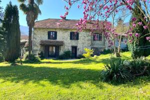 una casa de piedra con flores rosas en el patio en Gîte de groupe Petit Moya, Maison de Campagne, 13 personnes., en Arbas