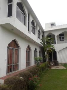 biały budynek z oknami i zielonym dziedzińcem w obiekcie Vamoose Raj Palace w mieście Bharatpur