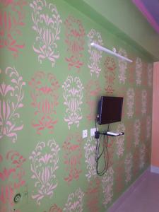 Habitación con TV en la pared y papel pintado en Vamoose Raj Palace, en Bharatpur