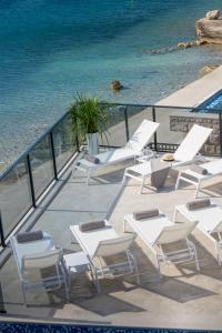薩諾的住宿－Ville Sol Del Mar，一组白色的椅子和桌子,旁边是水