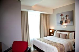 a hotel room with a bed and a red chair at UTM Hotel & Residence in Kuala Lumpur