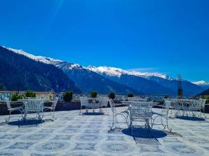 une table et des chaises sur une terrasse avec des montagnes enneigées dans l'établissement Hotel Mountain Top, à Manali