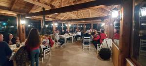 a group of people sitting at tables in a restaurant at Camping Farm Shelegur in Leskovik