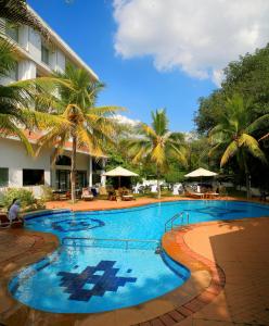 una piscina con palmeras y un hotel en Sangam Hotel, Thanjavur, en Thanjāvūr