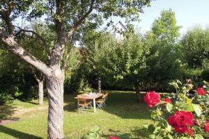 a table in a yard with roses and a tree at Le Verger - Maison de vacances Route des Vins in Hunawihr