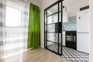 cocina con cortinas verdes y nevera en Victus Apartamenty, Apartament Sunshine, en Sopot