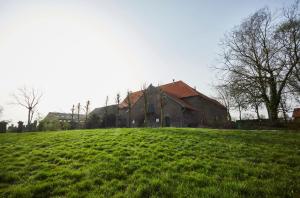 una iglesia en un campo de hierba al lado de un edificio en Carréhoeve in het iconisch heuvellandschap, en Noorbeek