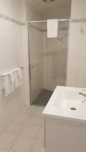 a white bathroom with a shower and a sink at Hotel Cavalier in Wantirna South