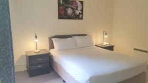 a bedroom with a white bed and two night stands at Hotel Cavalier in Wantirna South