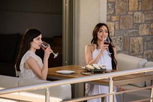 two women sitting at a table drinking wine at Costa D' Ifesto in Agios Ioannis Kaspaka