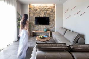 a woman in a white dress walking through a living room at Costa D' Ifesto in Agios Ioannis Kaspaka