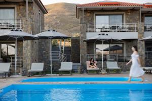 a woman in a white dress walking across a swimming pool at Costa D' Ifesto in Agios Ioannis Kaspaka