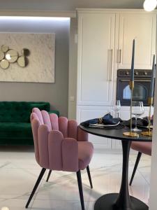 - un salon avec une table et une chaise rose dans l'établissement Marble Apartments, à Oradea