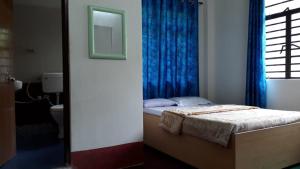 a bedroom with a bed with a blue curtain at Vamoose Rohini in Kurseong
