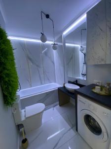 La salle de bains blanche est pourvue d'un lave-linge et d'un lavabo. dans l'établissement Marble Apartments, à Oradea