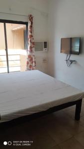 uma grande cama branca num quarto com televisão em Saritas Guest House - Bogmalo Beach em Bogmalo