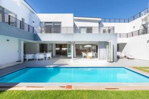 a villa with a swimming pool in front of a house at Stunning Villa de Soleil in Cape Town