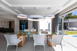 a dining room with a glass table and white chairs at Stunning Villa de Soleil in Cape Town