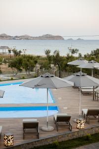 a swimming pool with umbrellas and chairs next to a pool at Costa D' Ifesto in Agios Ioannis Kaspaka