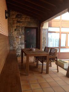 a wooden table and chairs in a room with a stone wall at Casa Rural La LLosina in Demués