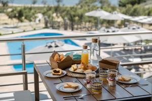 a table with food and drinks on a balcony with a pool at Costa D' Ifesto in Agios Ioannis Kaspaka