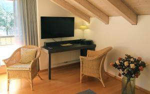 um quarto com uma secretária, uma televisão e 2 cadeiras em Bergblick em Garmisch-Partenkirchen