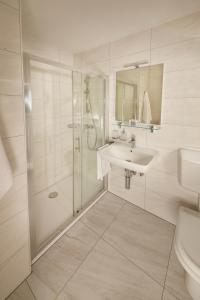 a white bathroom with a shower and a sink at Villa Bor - Hotel & Resort Adria Ankaran in Ankaran
