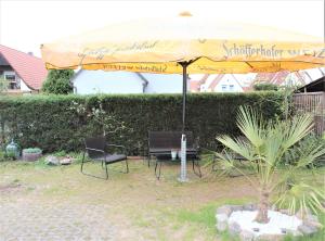 a yellow umbrella with two chairs and a table at Fewo- und Monteurswohnung Morgentau in Germersheim