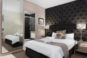 1 dormitorio con 1 cama grande y espejo grande en Kaya Stay, en Ciudad del Cabo