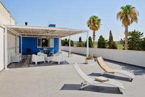 um pátio com mobiliário branco e palmeiras em Rivabella Deluxe Apartments em Rivabella