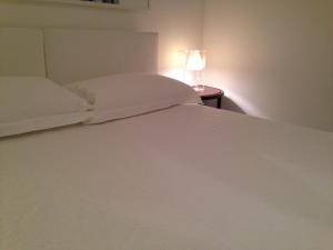 a bed with white sheets and a lamp on a table at Villa Masai in Ostuni
