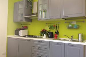 una cucina con pareti verdi, armadi bianchi e lavandino di Nel cuore di Como a Como