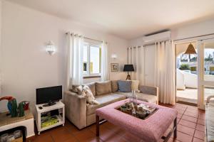 ein Wohnzimmer mit einem Sofa und einem TV in der Unterkunft Casa O12 in Vilamoura