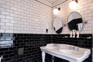 a black and white bathroom with two sinks and mirrors at The Canford in Poole