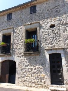 a stone building with two windows with potted plants at Gîte Le Barry in Le Caylar
