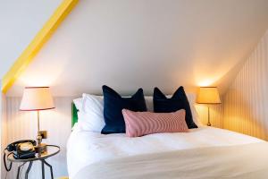a bedroom with a white bed with blue and pink pillows at The Canford in Poole