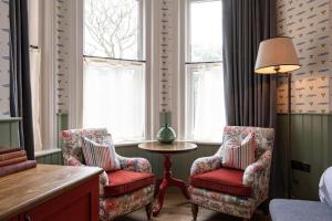 a room with two chairs and a table and windows at The Canford in Poole