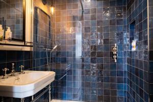 a blue tiled bathroom with a sink and a mirror at The Canford in Poole