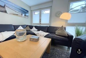 ein Wohnzimmer mit einem schwarzen Ledersofa und einem Couchtisch in der Unterkunft Strandvilla Baabe 10 HERZMUSCHEL in Baabe