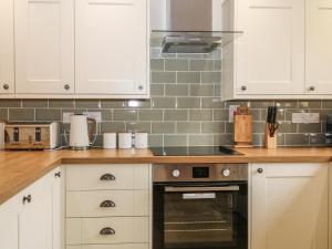 une cuisine avec des armoires blanches et un four dans l'établissement Thrushel Cottage, à Lifton 11 autres photos